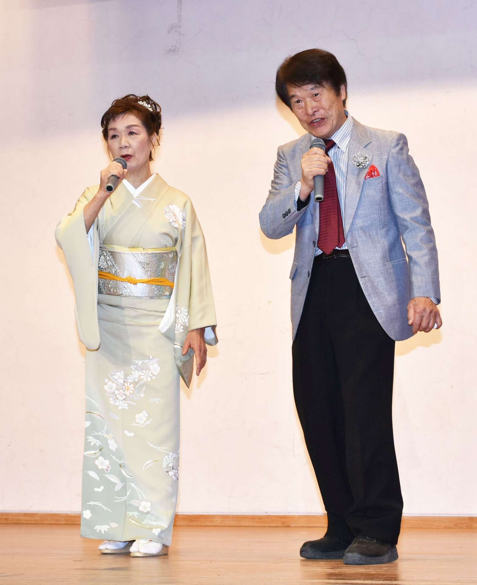 「伊佐の響き」を歌う田畑重光さん、美津子さん夫妻＝伊佐市文化会館