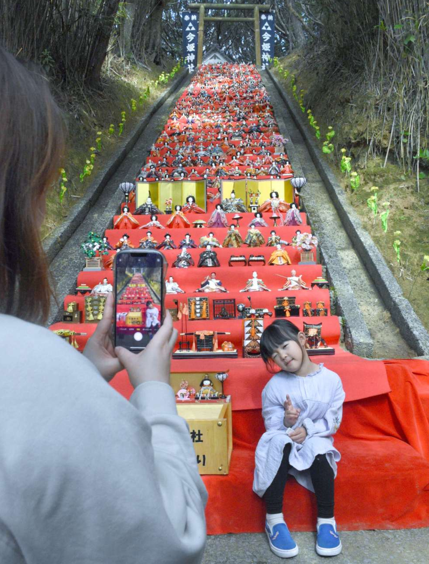 ひな飾りの前で写真を撮る親子＝１日、中種子町増田
