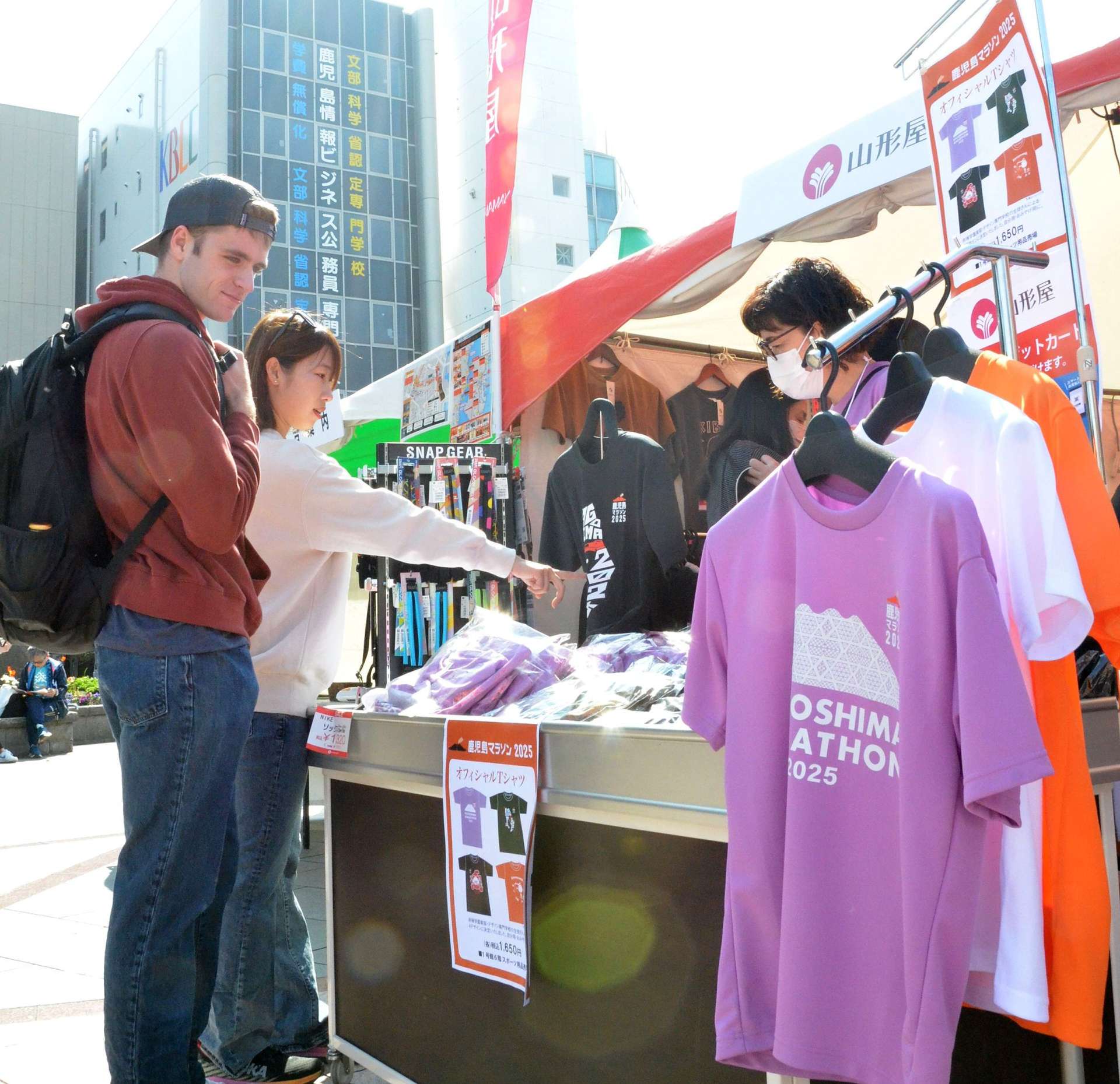 おもてなし広場で大会グッズを購入するランナー＝１日、鹿児島市の中央公園
