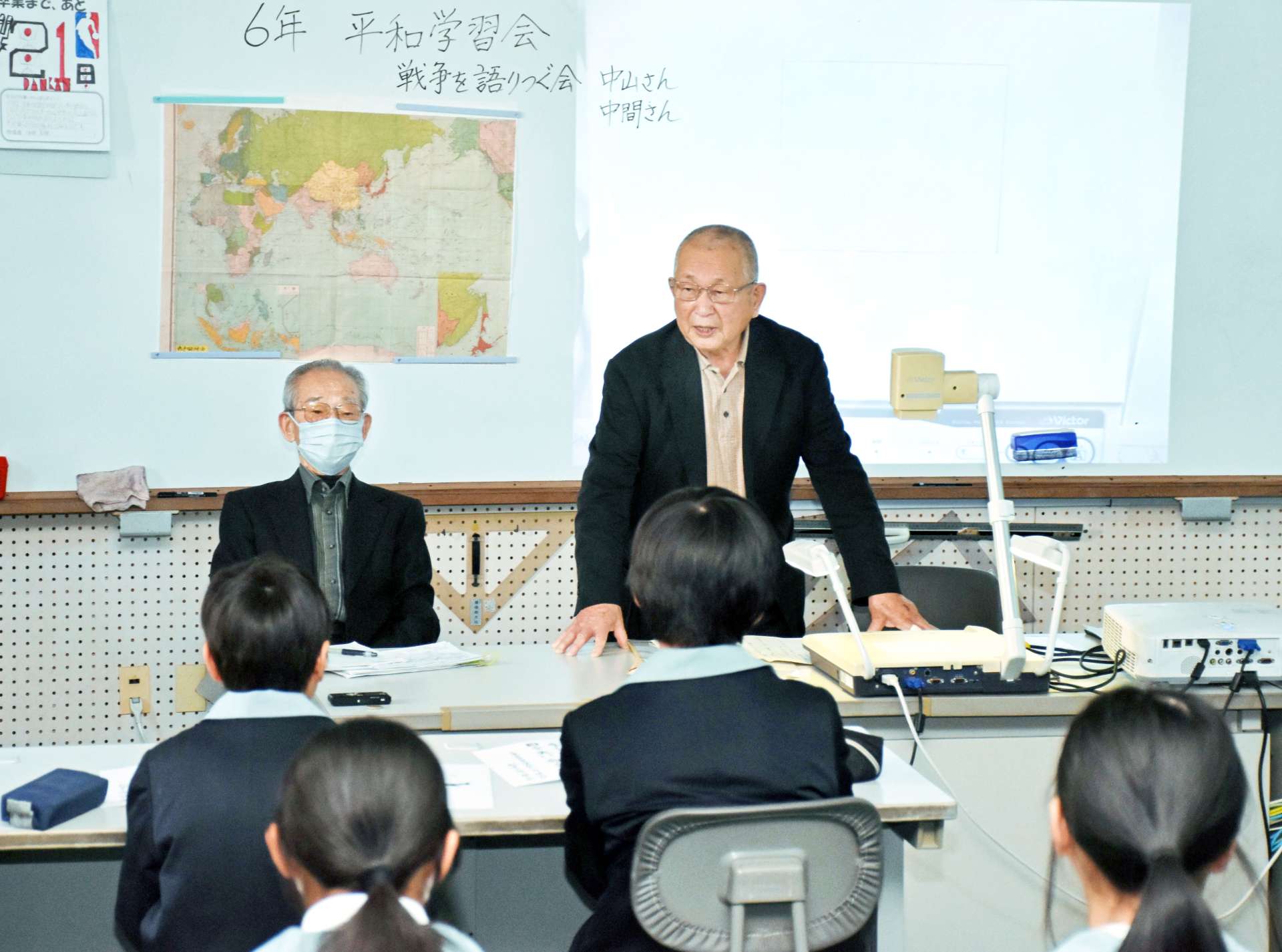 〈関連〉戦争体験を児童に紹介する中間啓行さん（右）と中山重雄さん＝いちき串木野市の照島小学校