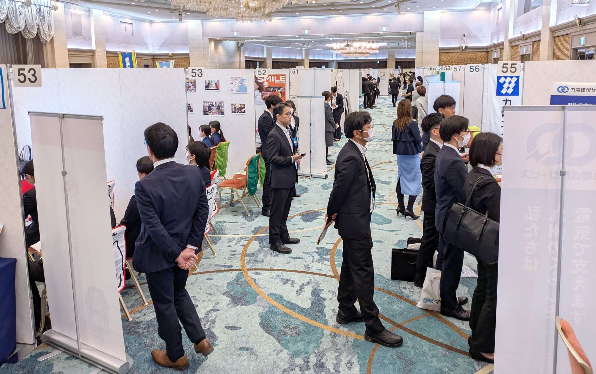 各企業のブースで担当者の説明に耳を傾ける学生＝１日、鹿児島市の城山ホテル鹿児島