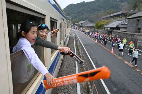 停止した車両からランナーに声援を送るツアー参加者＝２日、鹿児島市吉野町