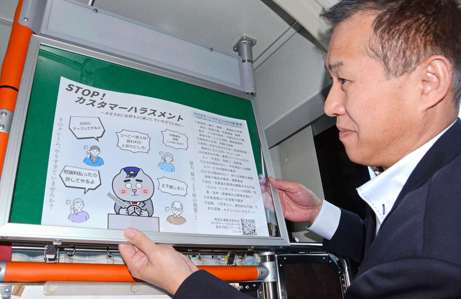 車内にポスターを張る阿多俊二鹿児島営業所副所長＝２月、鹿児島市小野町の南国交通鹿児島営業所