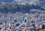 武岡公園予定地周辺は緑に覆われた丘陵地。左上の緑の屋根は長島美術館で、中央に樟南高校がある。手前に見えるのはＪＲ鹿児島中央駅や九州新幹線の線路＝２０２４年１月８日（本社チャーター機から撮影）