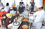 天川伸也シェフ（右）の調理に見入る児童たち＝屋久島町の神山小学校