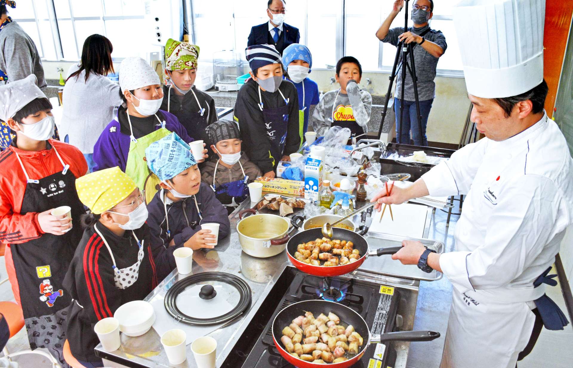 天川伸也シェフ（右）の調理に見入る児童たち＝屋久島町の神山小学校