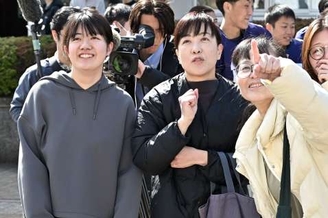 〈関連〉合格掲示板で自分の番号を確認し、笑顔を見せる受験生ら＝７日、鹿児島市郡元１丁目の鹿児島大学