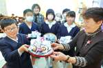 会員からフクロウのマスコットを受ける児童＝薩摩川内市の平佐西小学校