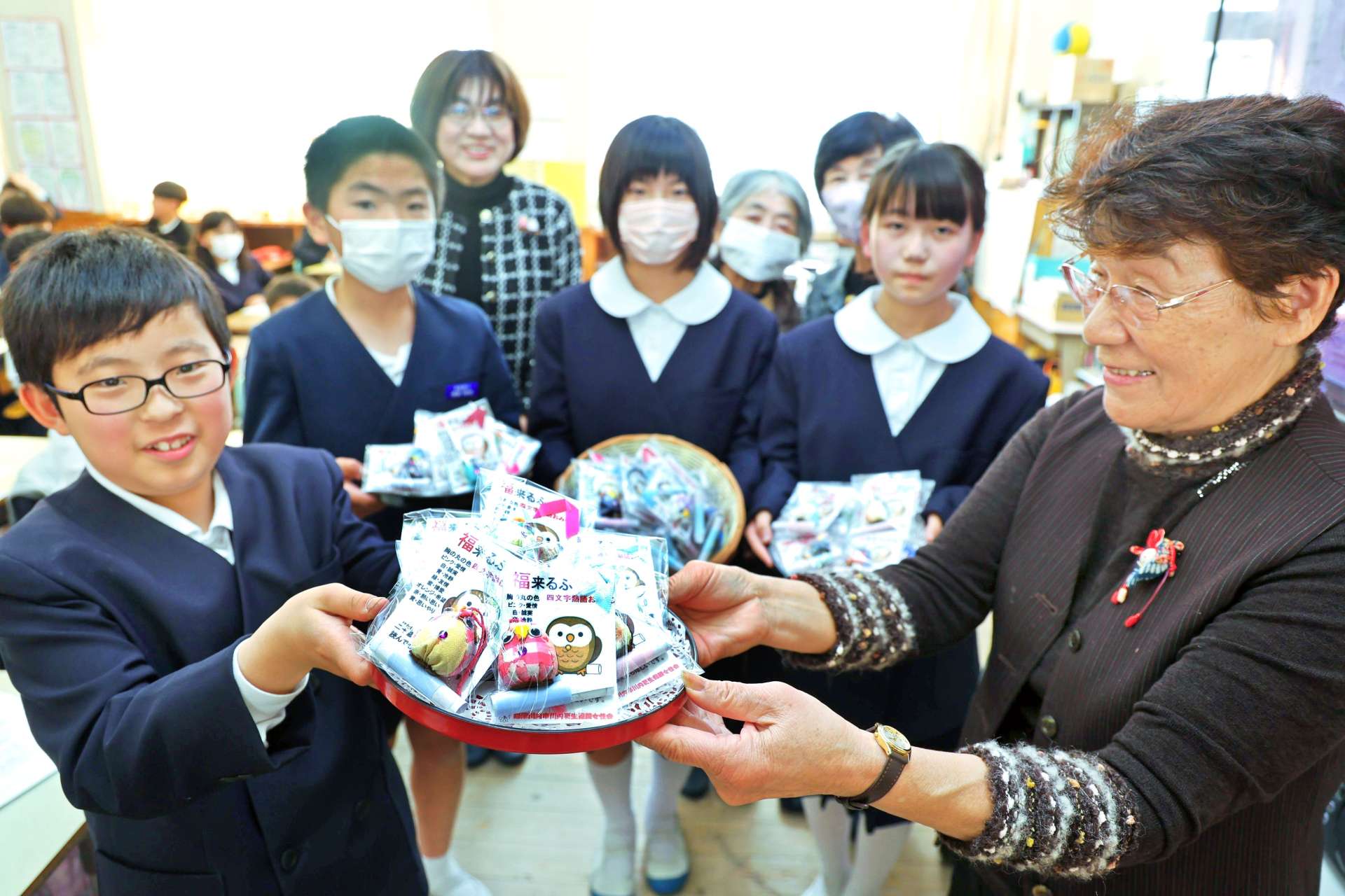 会員からフクロウのマスコットを受ける児童＝薩摩川内市の平佐西小学校