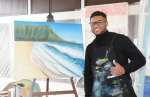 即興でハワイのダイヤモンドヘッドを描き、笑顔を見せるテヘレル・ポーターさん＝指宿市のＪＲ指宿駅