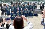 保護者が向けるカメラに笑顔を見せる西紫原中学校の卒業生＝１２日午前、鹿児島市