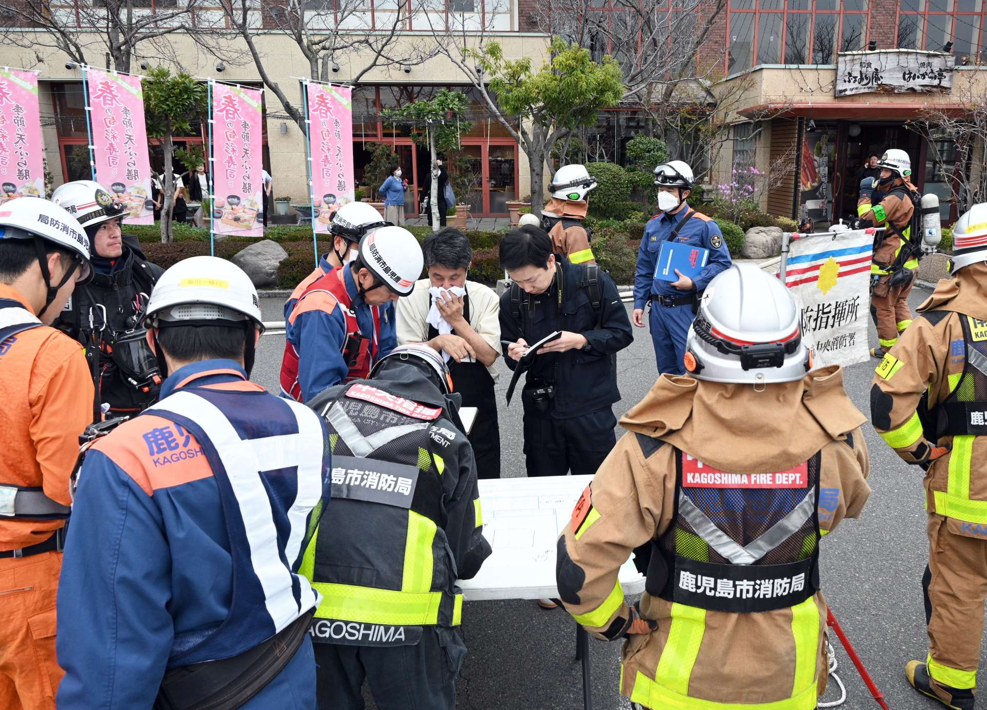 出火時の状況を聞く消防関係者ら＝１２日午後３時ごろ、鹿児島市与次郎１丁目