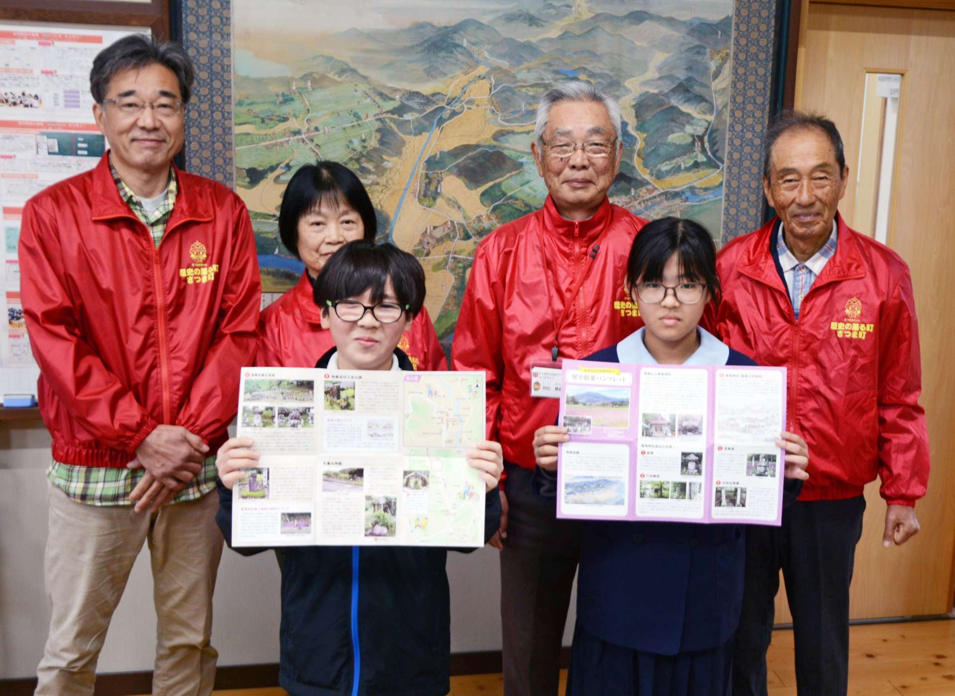 「さつまガイド」から柏原小学校に贈られた紫尾地区の歴史散策パンフレットを手にする児童ら＝さつま町柏原