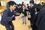 けん玉の基本を児童に教える葛賢伸さん（左）＝出水市の野田小学校