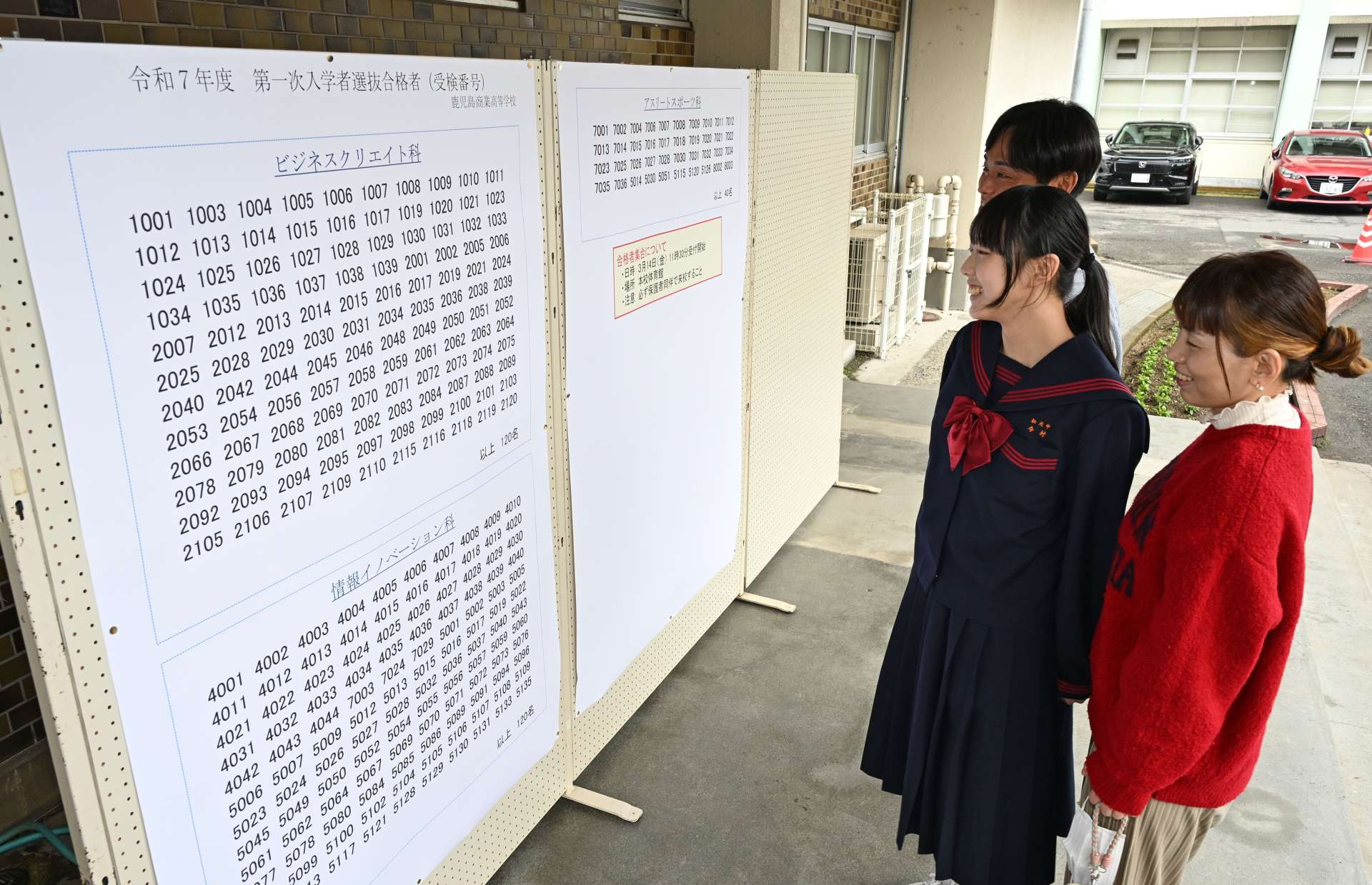 家族と受験番号を確認する受験生＝１３日、鹿児島市の鹿児島商業高校