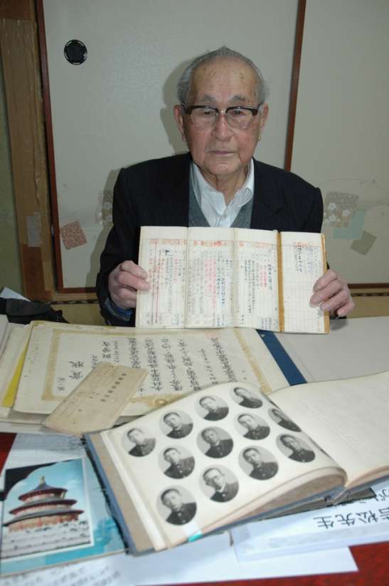 軍歴表など戦争当時の品々を手に話す若松与曽吉さん＝鹿児島市上福元町