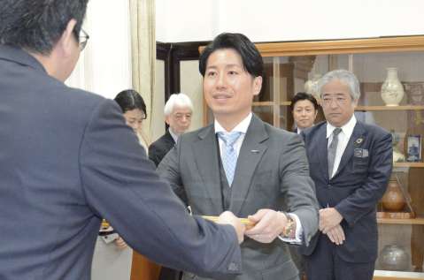 下鶴隆央市長から感謝状を受け取る新日本科学ＰＰＤの永田一郎社長（中央）＝１４日、鹿児島市役所