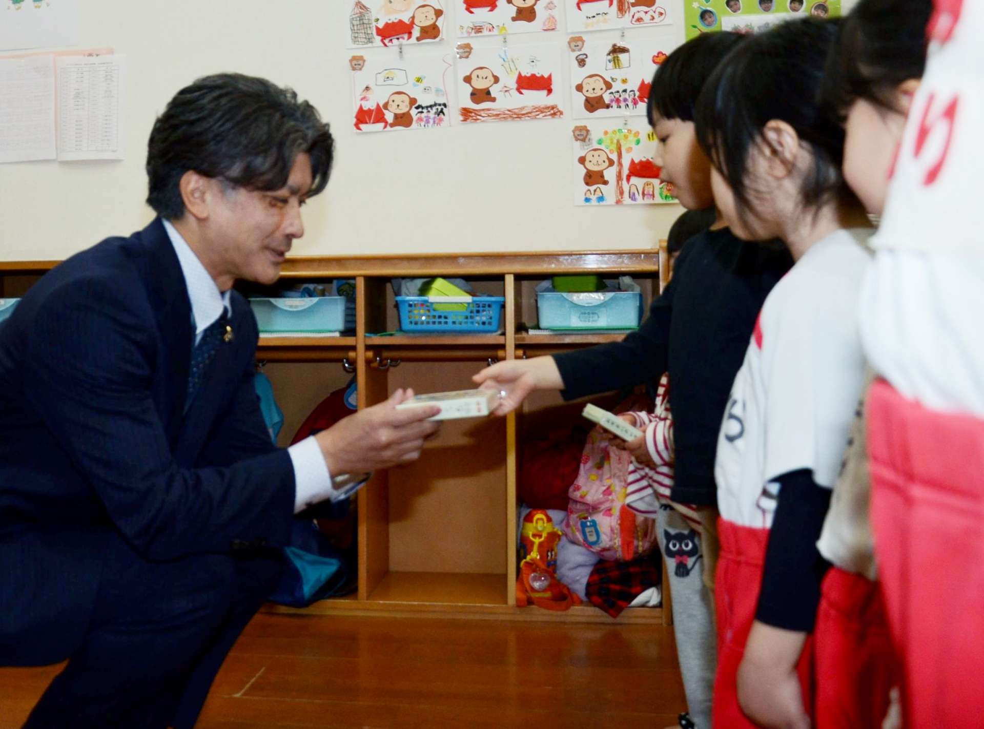 園児代表におやさいクレヨンを手渡す富国生命保険の中村慶嗣支社長（左）＝鹿児島市紫原３丁目のわくわく紫原中央保育園