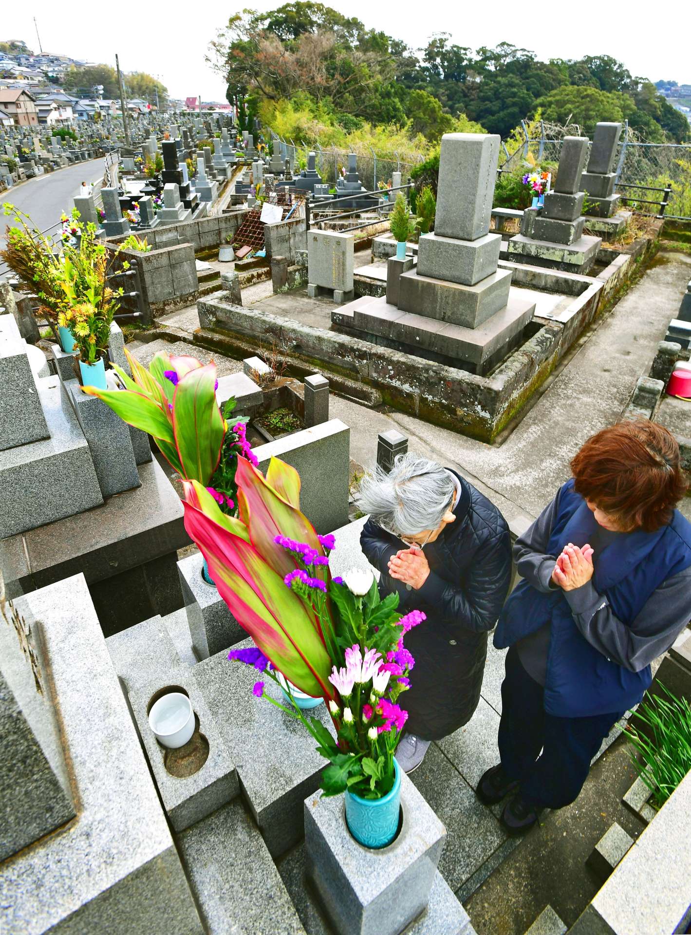 〈別カット〉先祖の墓を訪れ、手を合わせる親子連れ＝１７日午後、鹿児島市の坂元墓地