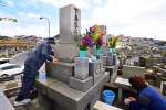 先祖の墓を訪れ、手を合わせる親子連れ＝１７日午後、鹿児島市の坂元墓地