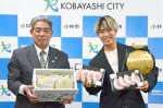 宮原義久・小林市長（左）から市産黒豚ステーキ肉とメロンを贈られ、笑顔の寺田匠選手＝市役所
