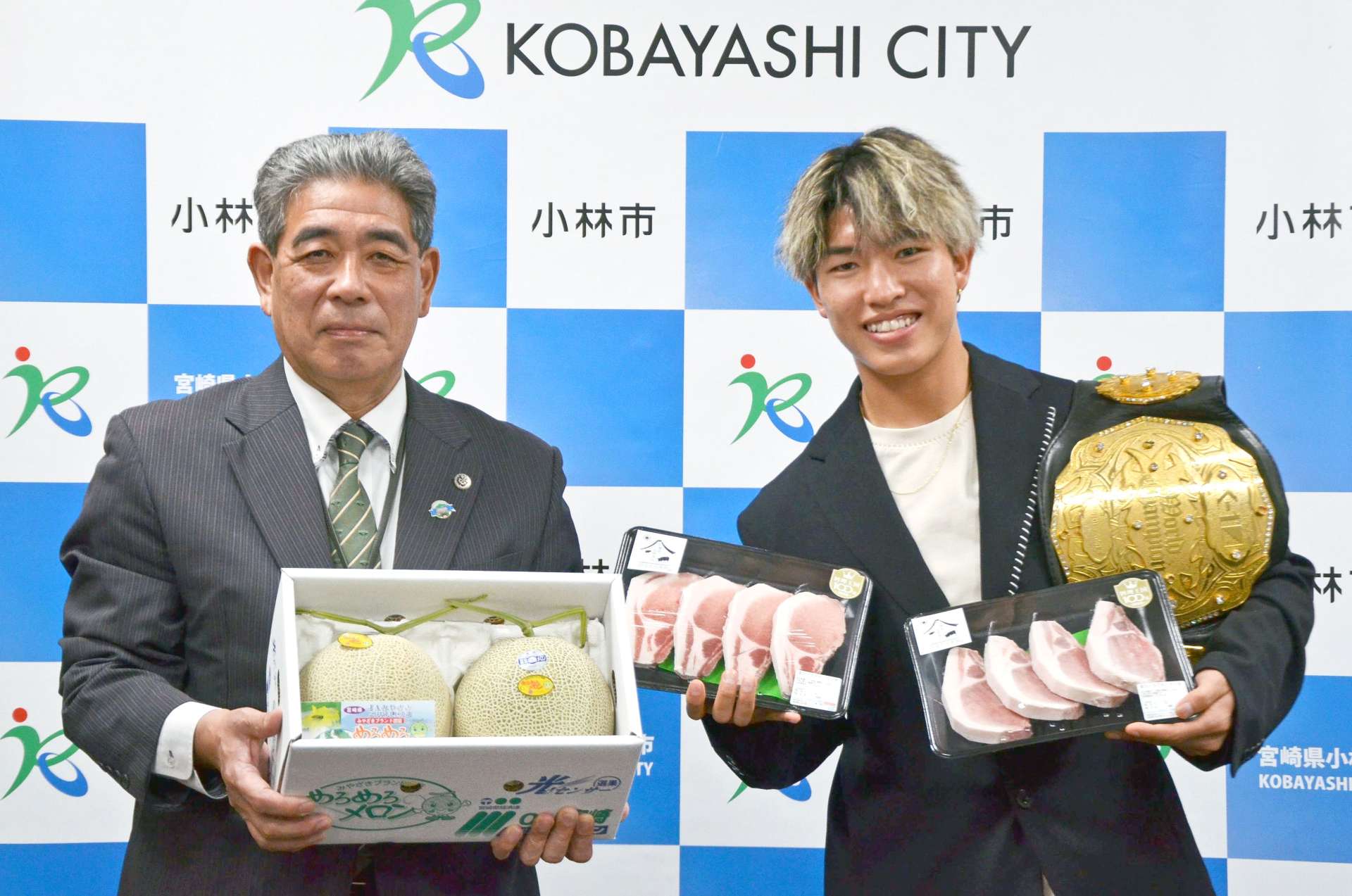 宮原義久・小林市長（左）から市産黒豚ステーキ肉とメロンを贈られ、笑顔の寺田匠選手＝市役所