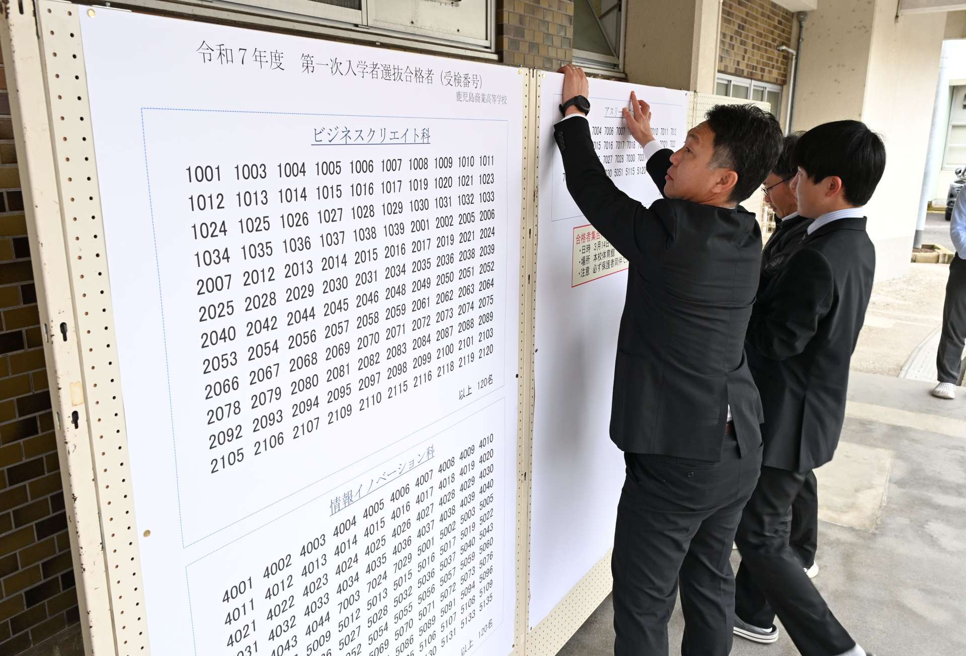 合格発表の紙を張り出す教員＝１３日、鹿児島市の鹿児島商業高校