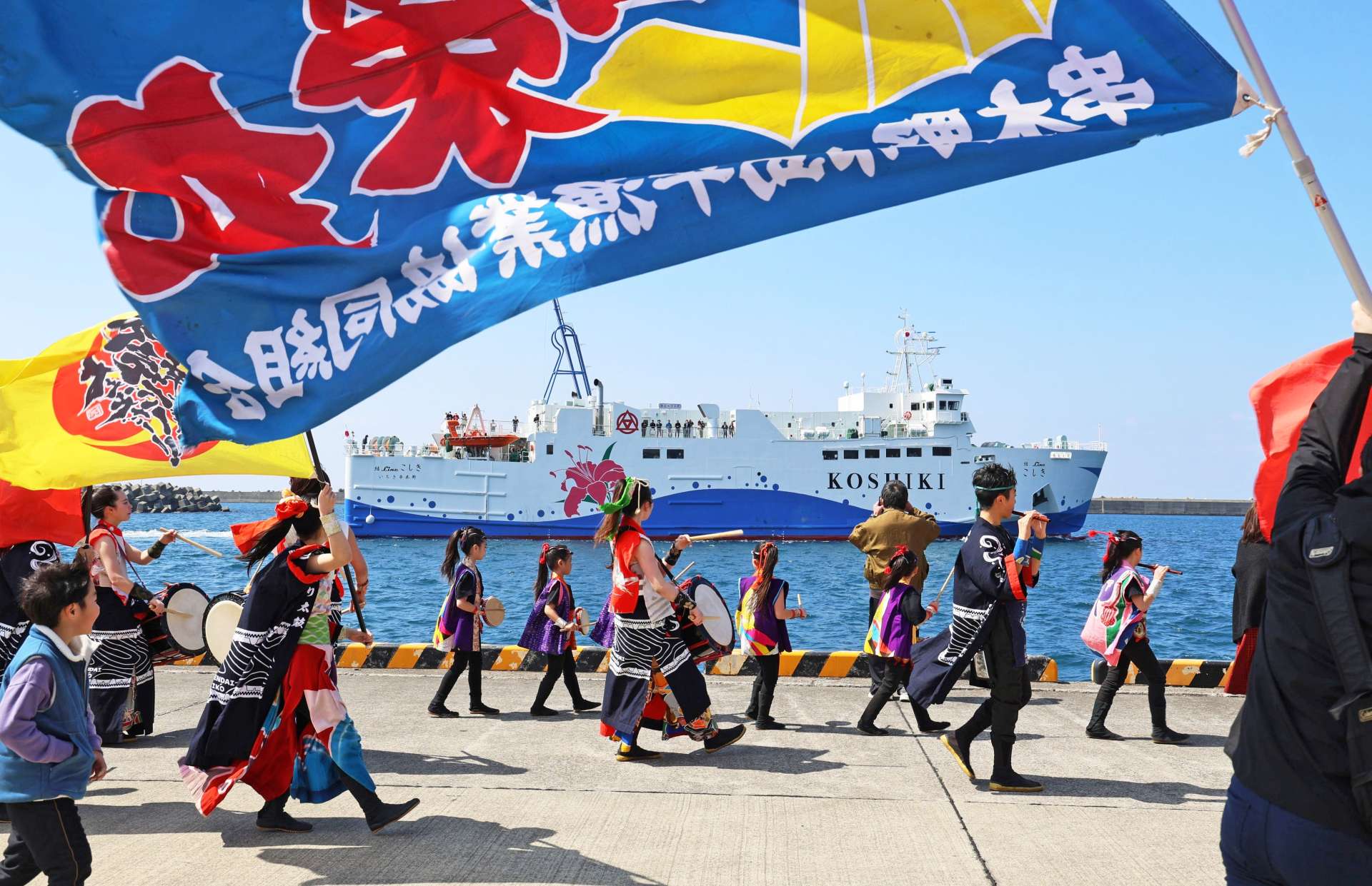 太鼓の演奏や大漁旗に見送られ、出港する「結Ｌｉｎｅこしき」＝２０日、いちき串木野市の串木野新港