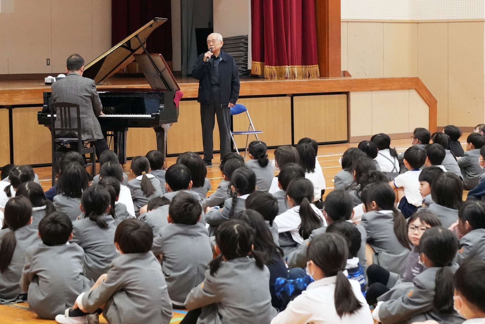 戦前の田崎小学校の校歌を歌う穂山睦男さん＝鹿屋市の同校