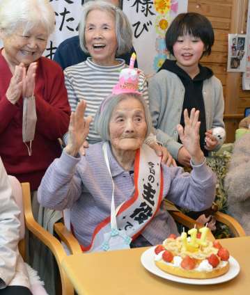 〈関連〉バースデーケーキのろうそくを吹き消し自ら万歳する坂下サトさん＝２０日、鹿児島市星ケ峯２丁目