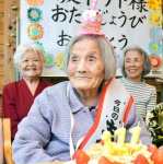 カチューシャを着け、誕生日祝いのケーキを前に笑顔を見せる坂下サトさん＝２０日、鹿児島市星ケ峯２丁目