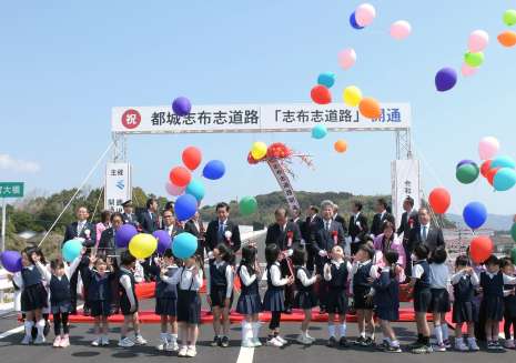 テープカットやくす玉、バルーンリリースで開通を祝う関係者＝２３日、志布志市志布志町安楽
