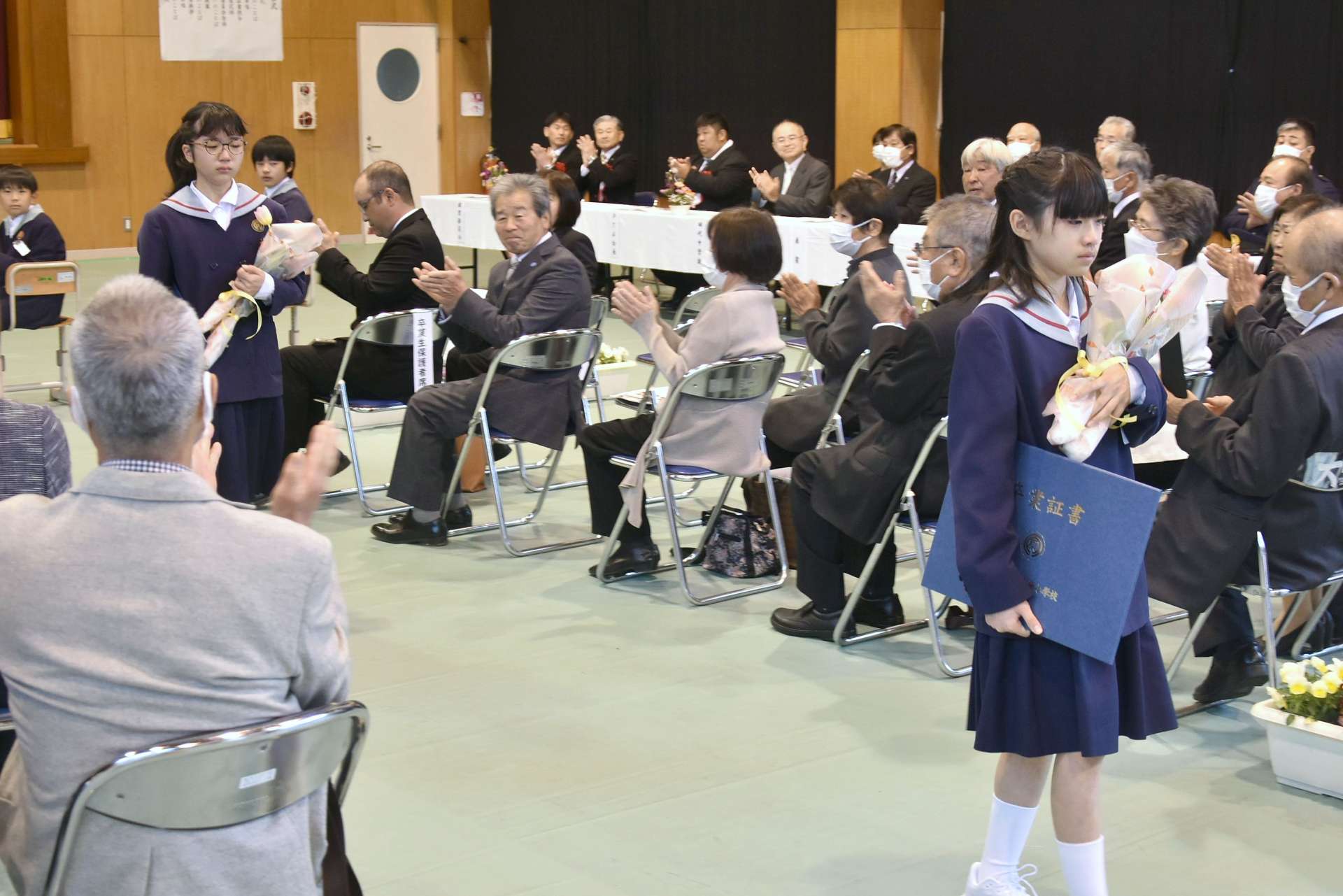 拍手で見送られる大原小学校の卒業生＝２４日、錦江町田代の同校