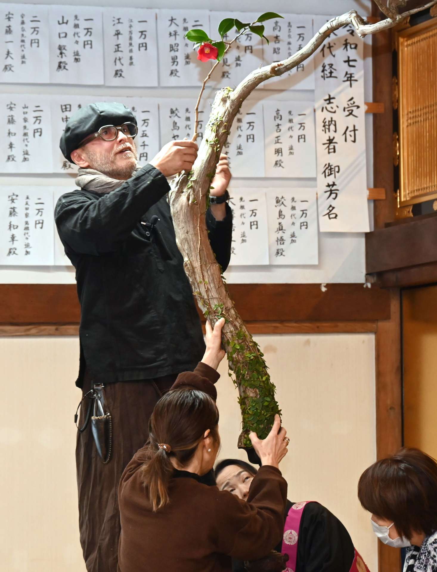 枯れ木にツバキの花を飾る上野雄次さん＝南九州市知覧の教行寺