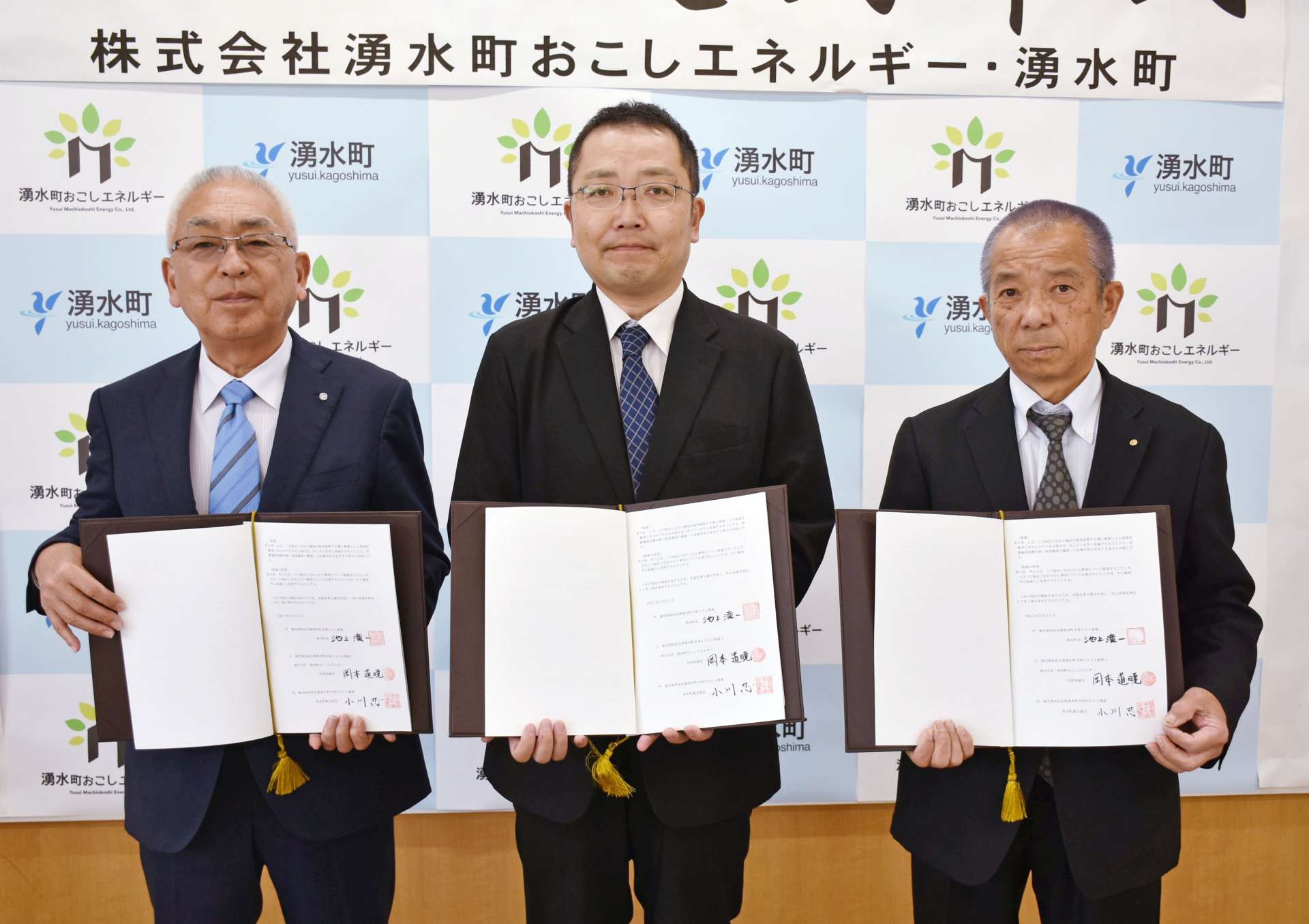 調印する湧水町おこしエネルギーの岡本道暁社長（中央）と池上滝一町長（左）ら＝２５日、湧水町役場