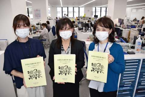 〈関連〉新型コロナウイルス感染症への対応記録誌を手に当時を振り返る職員＝２５日、姶良市役所