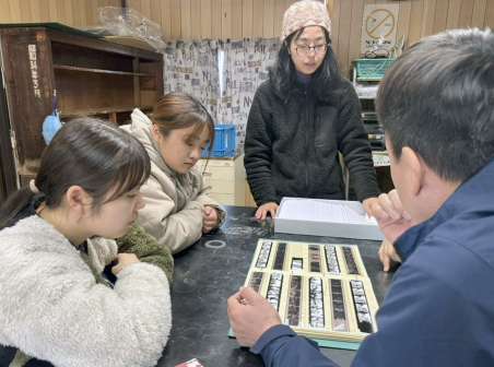 水俣病センター相思社が保管するネガフィルムを見る鹿児島大学の読書会メンバーら＝２月２０日、熊本県水俣市