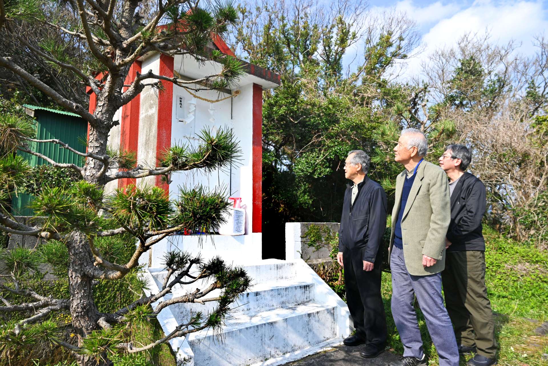 傷みの激しい枕崎神社を心配そうに眺める奉賛会の関係者ら＝枕崎市山手町