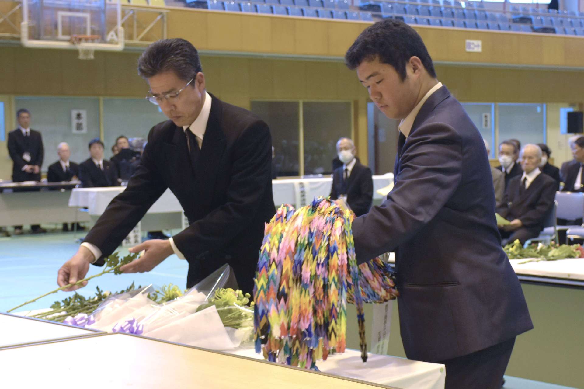 戦没者の冥福を祈り、献花する参列者＝２７日、指宿市の開聞総合体育館