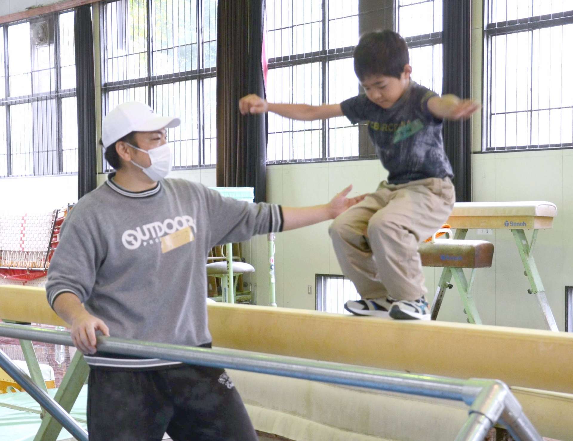 小学生にパルクールの基本動作を教える田尻祐介さん（左）＝鹿児島市の県総合体育センター補助体育館