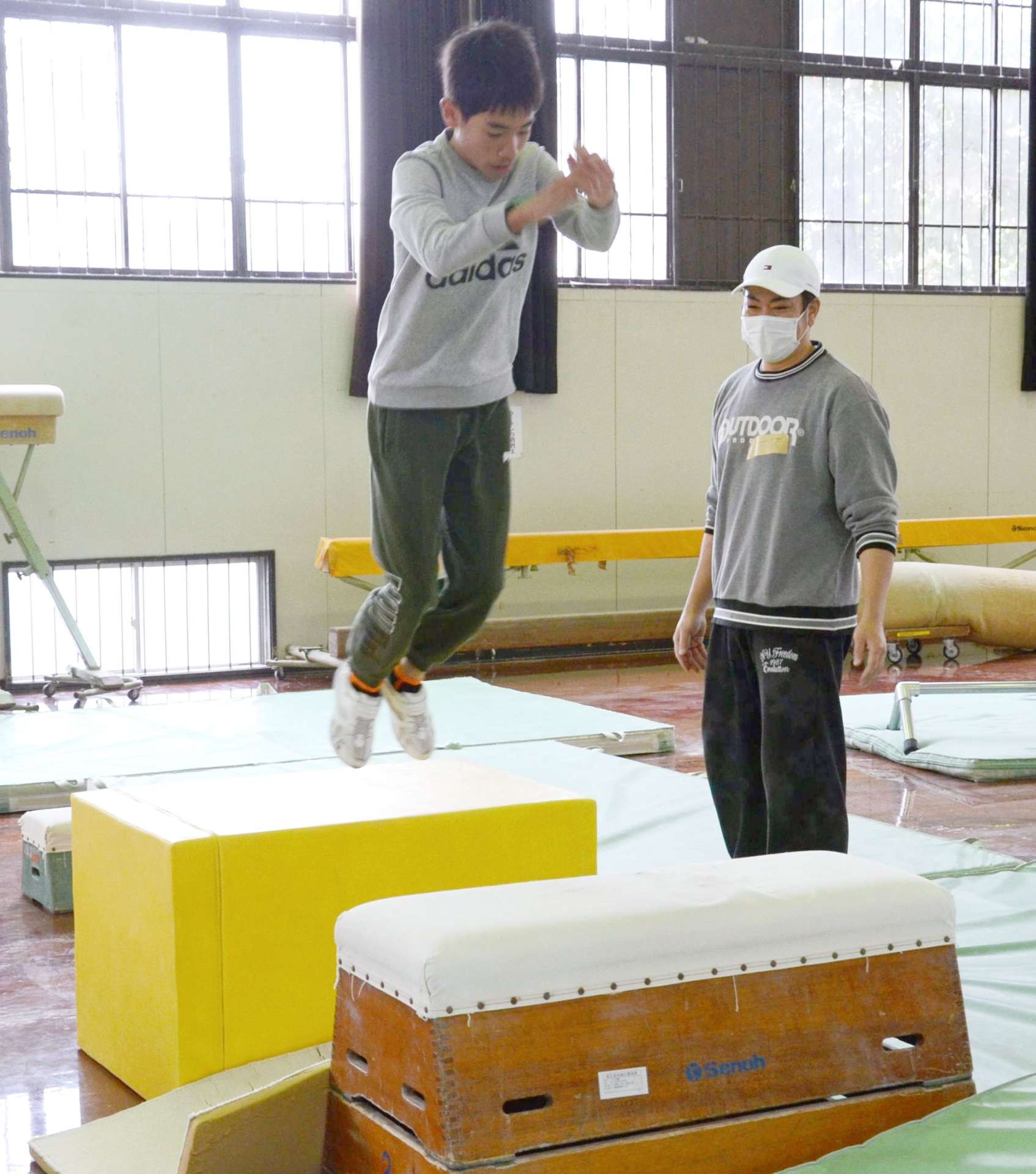 小学生にパルクールの基本動作を教える田尻祐介さん（右）＝鹿児島市の県総合体育センター補助体育館