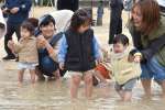 赤ちゃんの足を海につけて無病息災を祈る家族連れら＝３１日、奄美市笠利の用安海岸