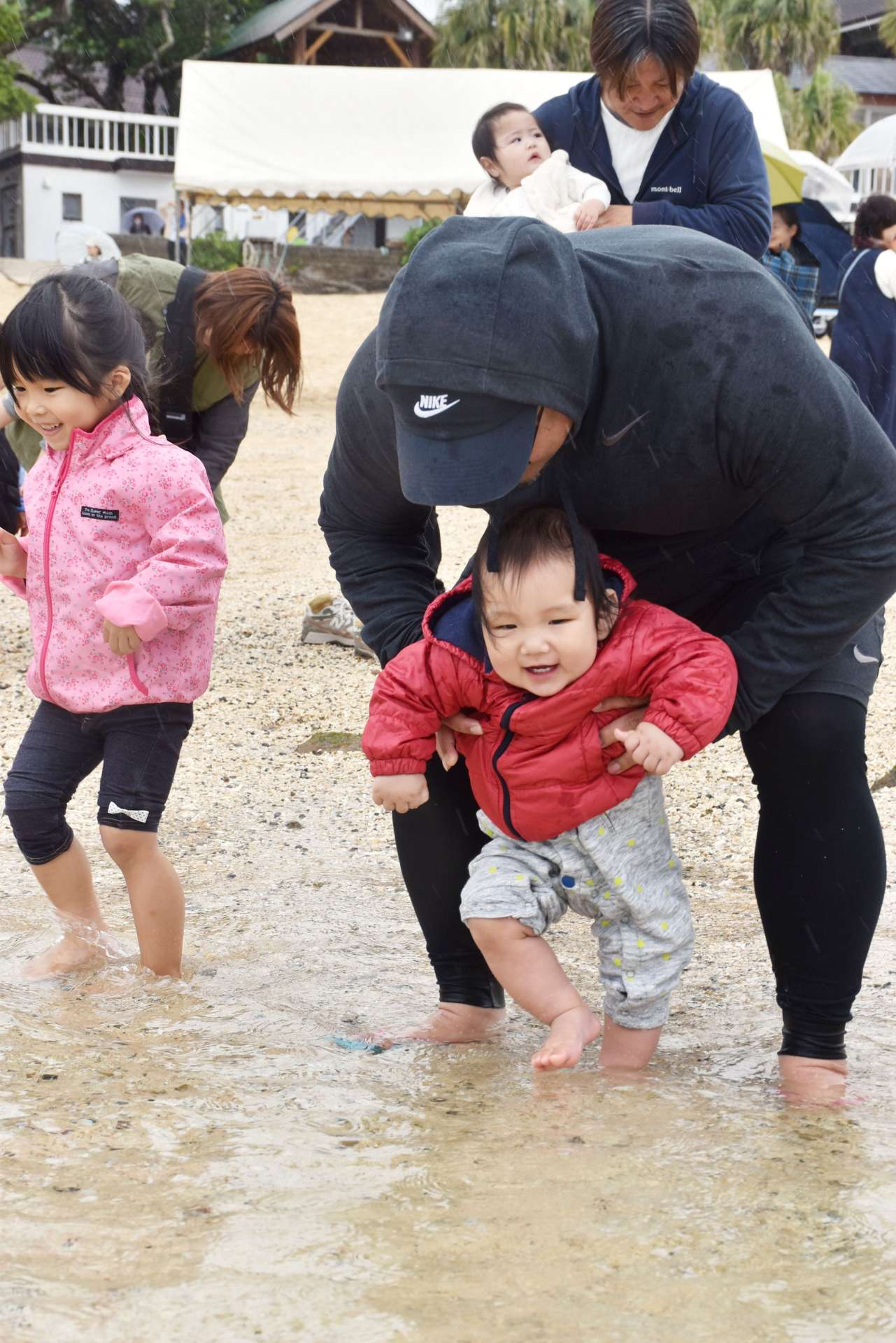 赤ちゃんの足を海につけて無病息災を祈る家族連れら＝３１日、奄美市笠利の用安海岸