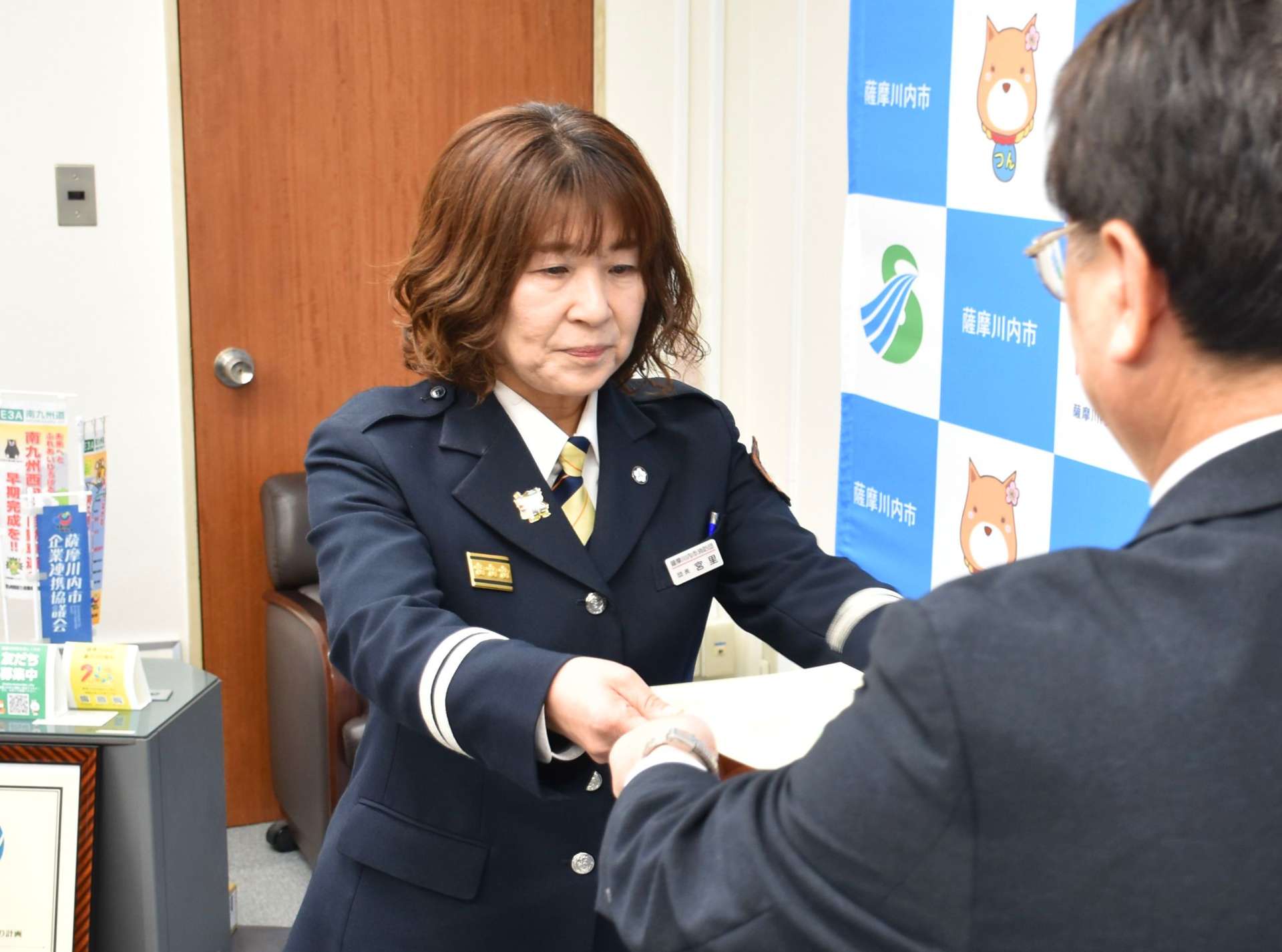 薩摩川内市消防団長の辞令を受け取る宮里英子さん（左）＝１日、薩摩川内市役所