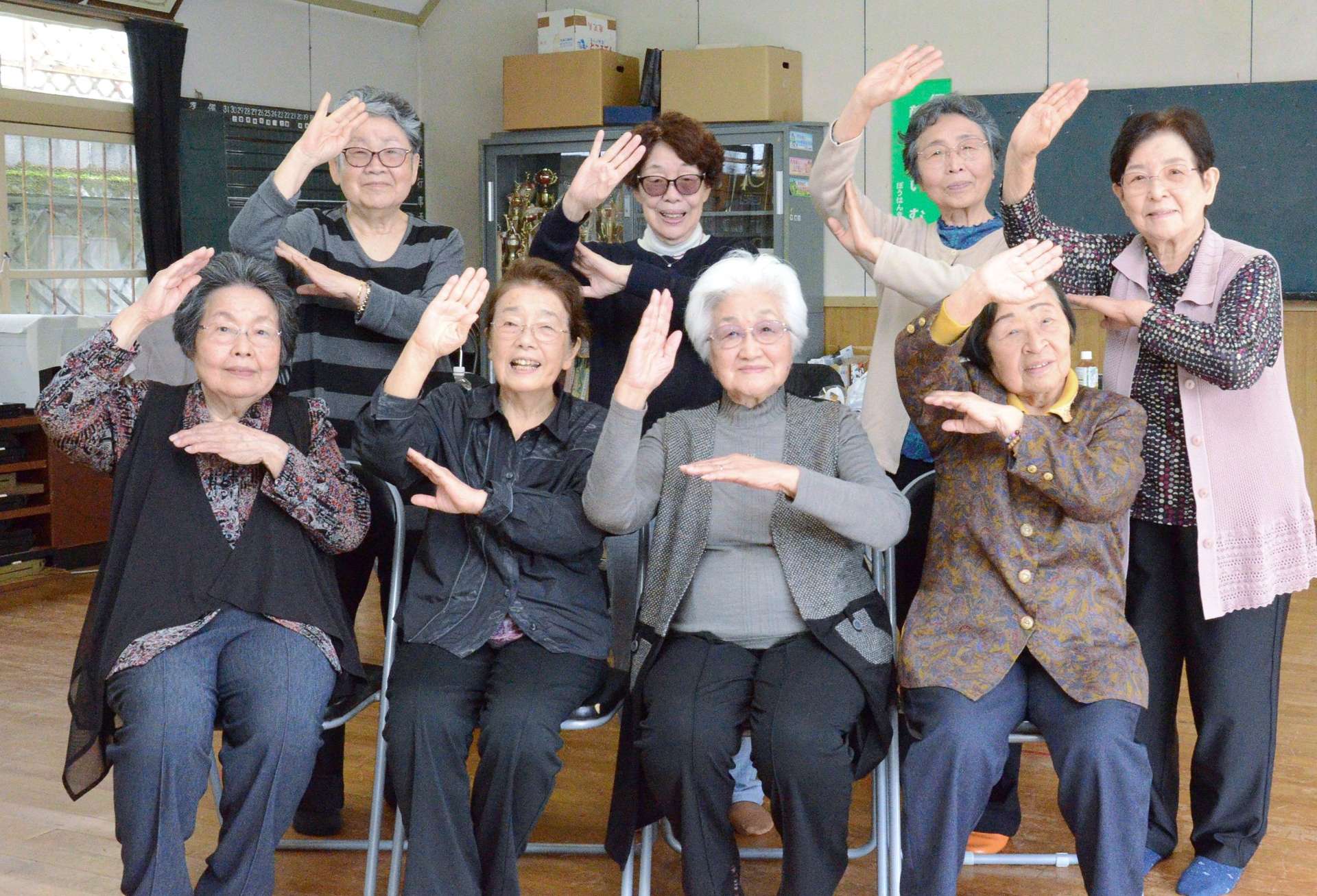 笑顔で手踊りのポーズを決める「水曜会」のメンバー＝３月２６日、鹿児島市明和５丁目の永吉団地親和会館