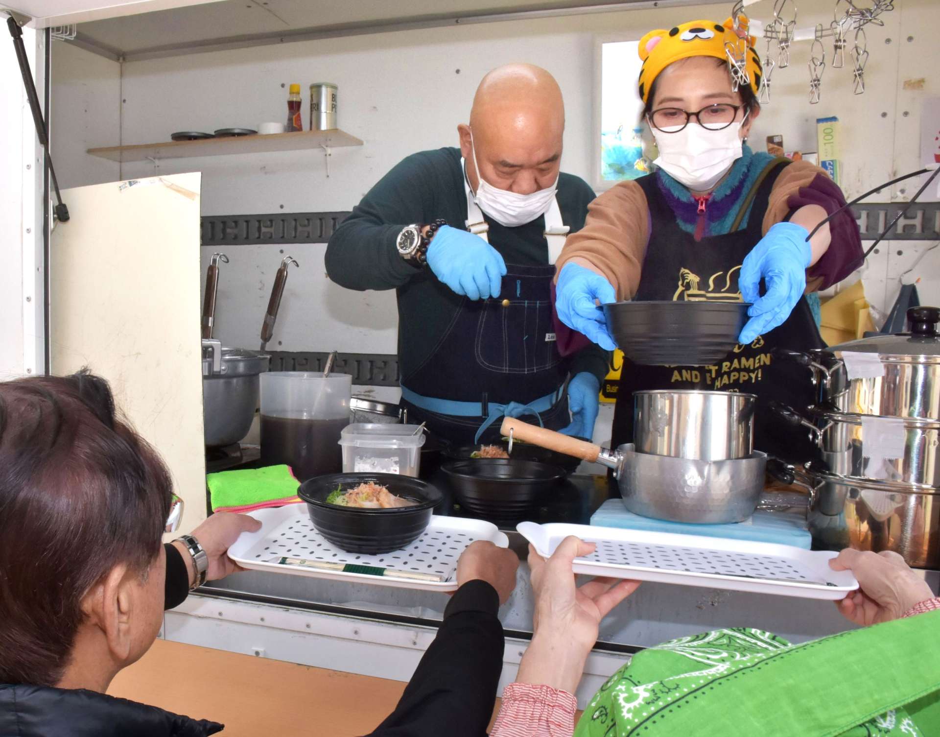 キッチンカーでラーメンを作る桑畑愛子さん（右）と梶原貞治さん＝３月３０日、長島町の蔵之元公民館