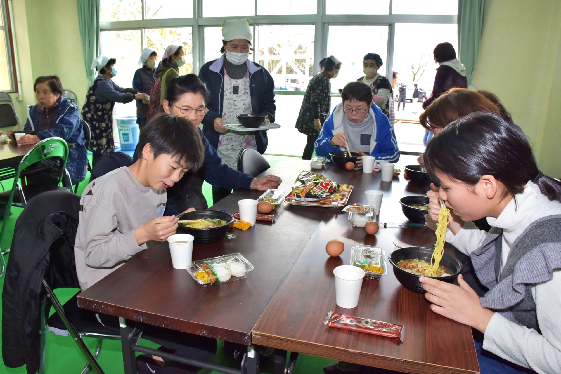 熱々のラーメンをすする蔵之元地区の住民ら＝３月３０日、長島町の蔵之元公民館