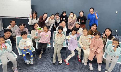 出来上がった工作を手に記念撮影する参加者と学生たち