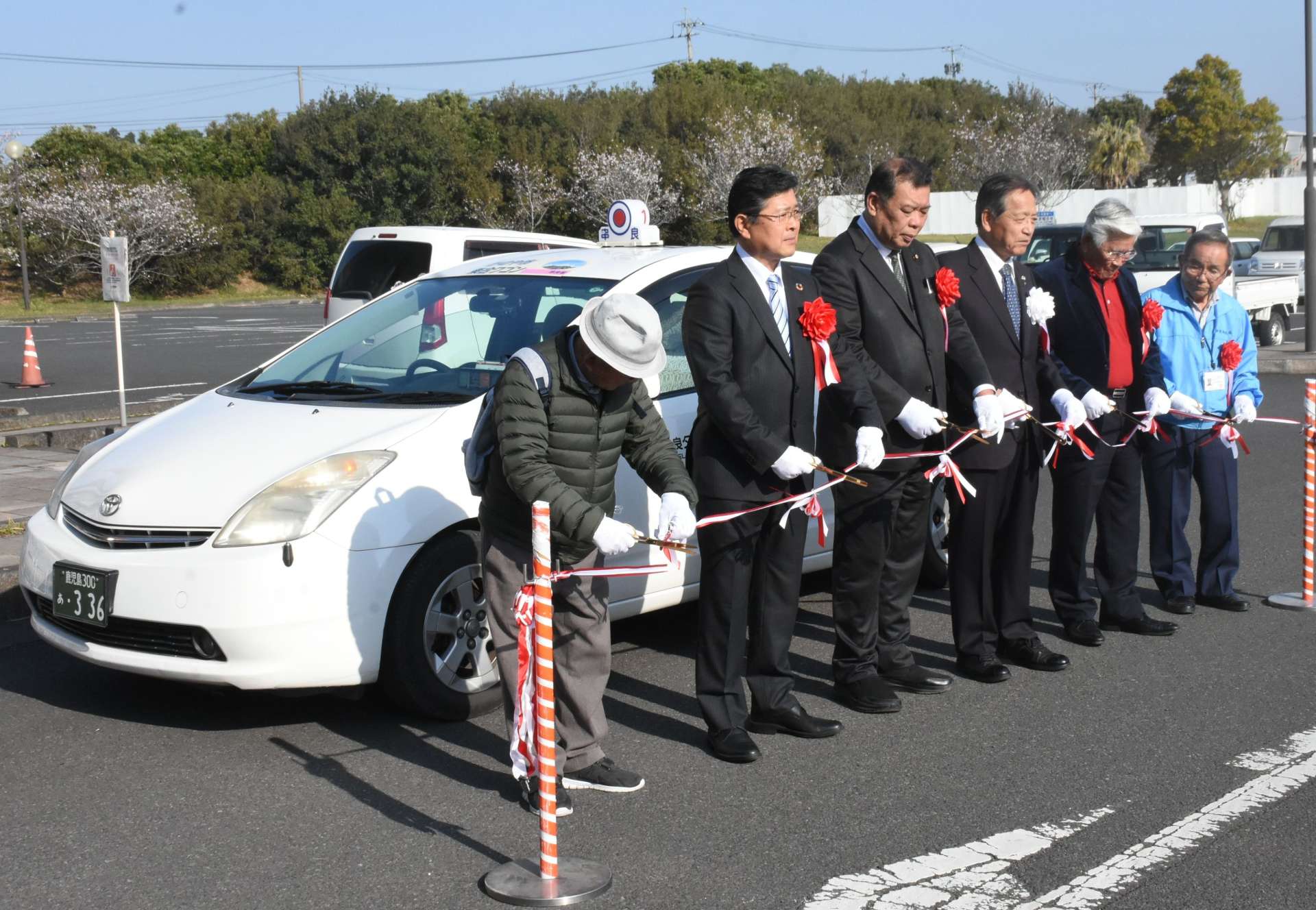 乗り合いタクシーの運行開始を祝いテープカットする関係者＝４日、鹿屋市の串良さくら温泉前