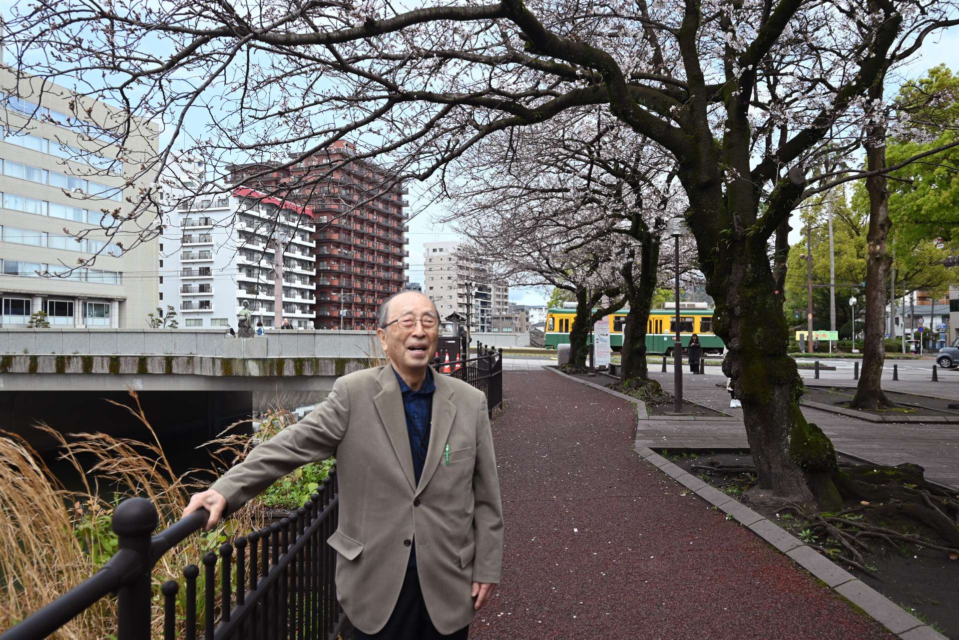 遅咲きの花を付けた桜に目を細める仙田淳一さん＝鹿児島市加治屋町